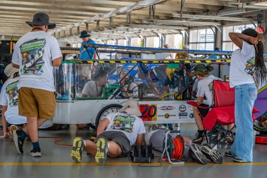 Students maintaining their solar car in the race paddock